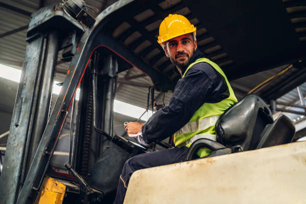 istock Man worker at forklift driver happy working in industry factory logistic ship. Man forklift driver in warehouse area. Forklift driver sitting in vehicle in warehouse 1496703130