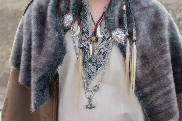 Viking man ornaments, Viking fang pendants and Viking chains with metal animal heads, the hammer etc... He also wears a collar of shaggy animal hair. All in the foreground on the man's chest