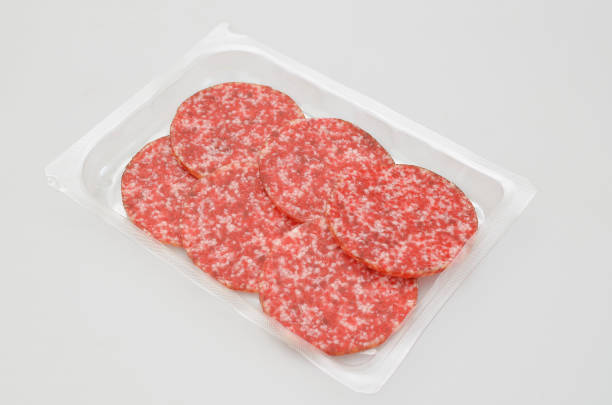 Slices of Salami in a plastic box, isolated on white background stock photo