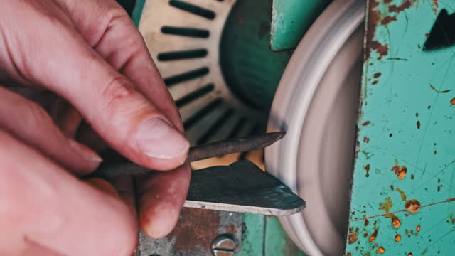 Hands of a Craftsman Working on an Abrasive Wheel in a Workshop