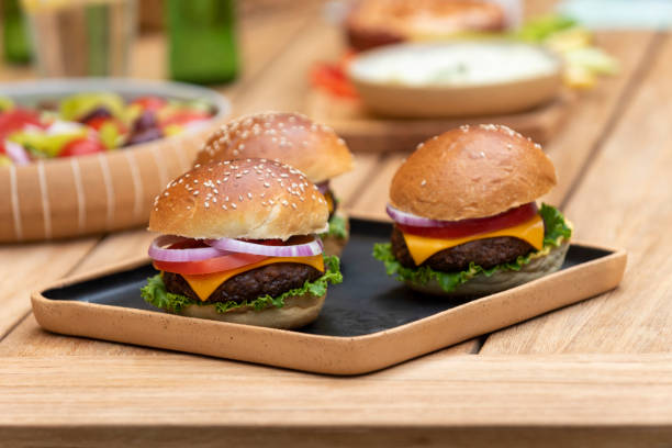 three vegan burgers on a wooden plate stock photo