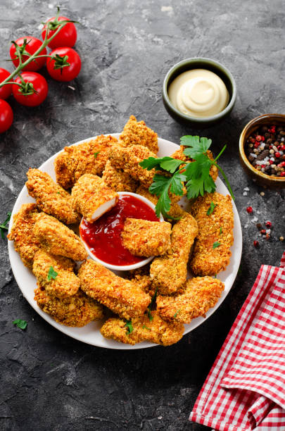 istock Delicious Crispy Fried Breaded Chicken Breast Strips with Ketchup on Dark Background 1496716620
