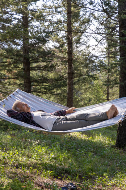istock Senior male relaxes in a hammock in the forest 1496720427