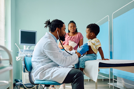 African American kid being examined with stethoscope during medical checkup at pediatrician's.