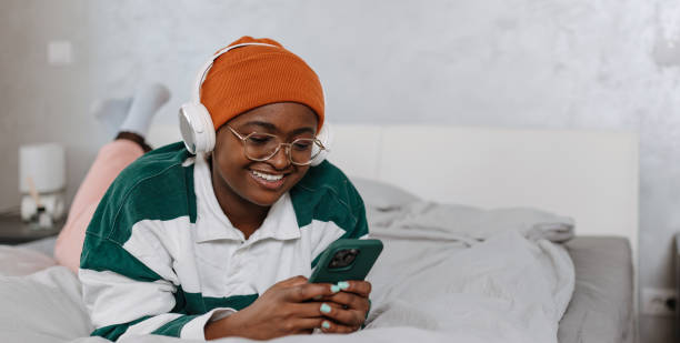 istock Young woman lay in her bed using mobile phone and smiling 1496721897