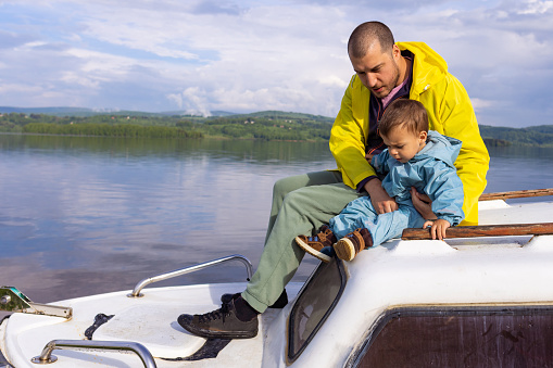 Sharing a special bond, a man and his young son sit side by side on a small boat.