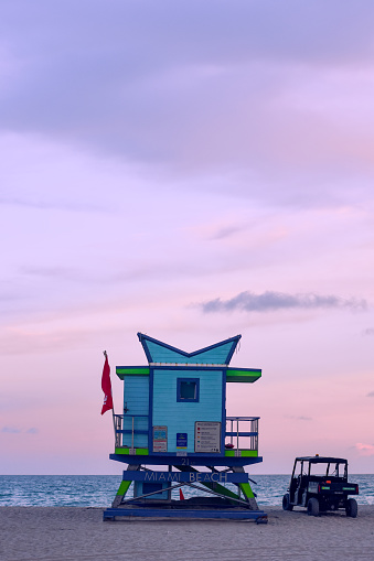 A lifeguard tower and four wheeler on the beach in Hawaii with a purple sky behind them