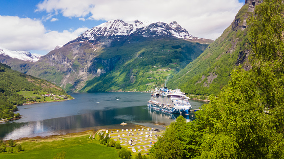 Geiranger, Norway- May 30, 2023-The luxury cruise ship, NCL Prima, makes a port of call visit at the end of the beautiful Geiranger Fjord in Geiranger, Norway on a bright, clear late May afternoon.