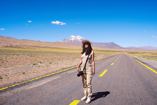 portrait full length woman photographer hiker walking on the road of San Pedro de Atacama