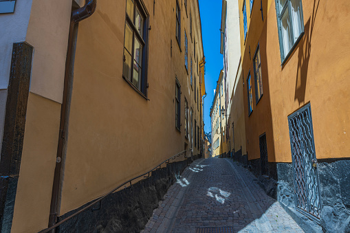 Beautiful view of narrow street between two yellow buildings with paving stone road. Sweden. Stockholm.