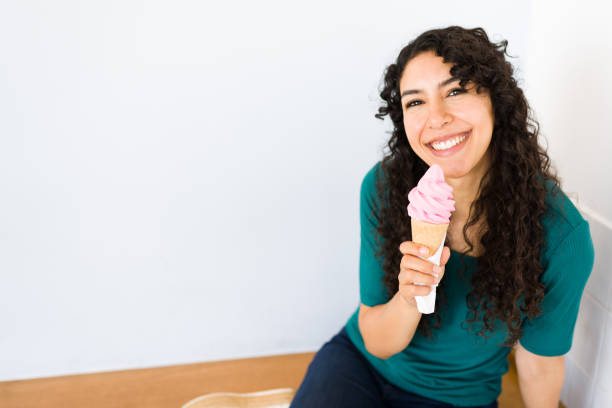 Smiling happy woman customer ready to eat an ice cream cone after buying a sweet cold treat for the summer