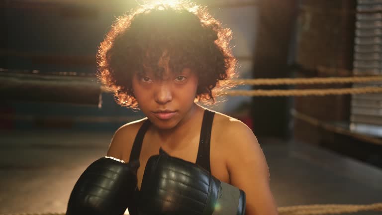 Outcry independent girl power. Angry african american woman fighter with boxing gloves looking serious aggressive to camera standing on boxing ring. Strong powerful girl looking concentrated straight.