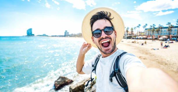 istock Handsome young man taking selfie with smart mobile phone device outside - Cheerful tourist enjoying summertime at the beach - Life style, traveling and technology concept 1496735311