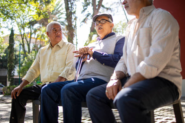 istock Three senior Latin friends sitting at the park and talking 1496738305