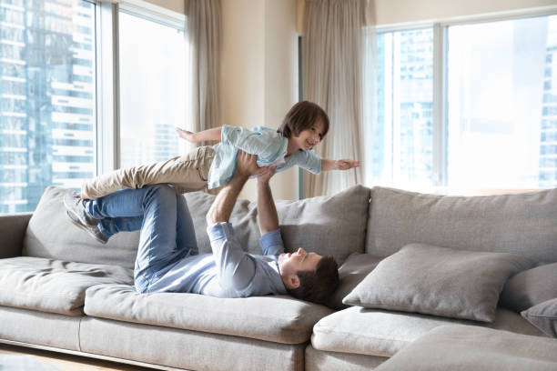 istock Strong dad lying on back, lifting happy little son up 1496738575