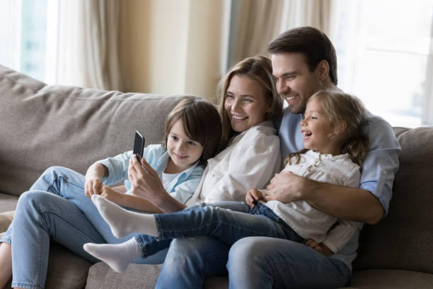 istock Young mother and father hugging cheerful kids on home sofa 1496738799