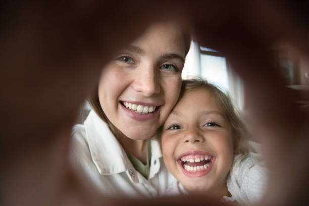 istock Cheerful mom and happy daughter kid making hand heart frame 1496739908