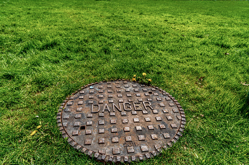 Round sewer cap or manhole cover on a grass field with 
