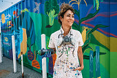 Mid adult Iranian woman artist painting  mural on shipping container