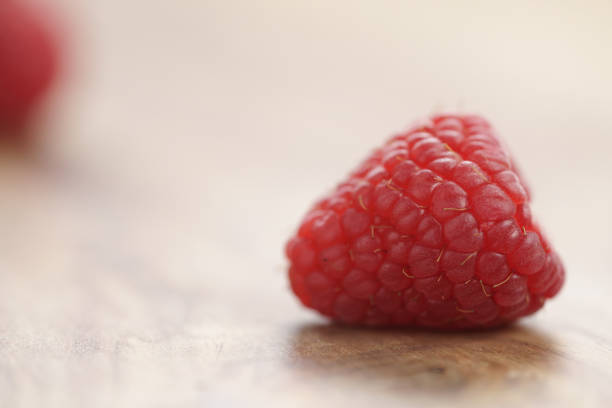 A macro perspective of a pile of ripe, red raspberries against a bright, white background. The berries' detailed texture and vivid color evoke freshness and a healthy lifestyle, making it ideal for culinary and wellness concepts. The composition emphasizes their natural vibrancy and nutritional appeal.
