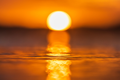 Close up of light reflecting on smooth ocean surface from sun setting.
