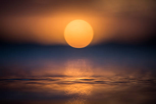 istock Close up of light reflecting on smooth ocean surface from sun setting 1496744259