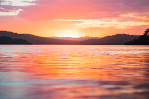 Close up of light reflecting on smooth ocean surface from sun setting.