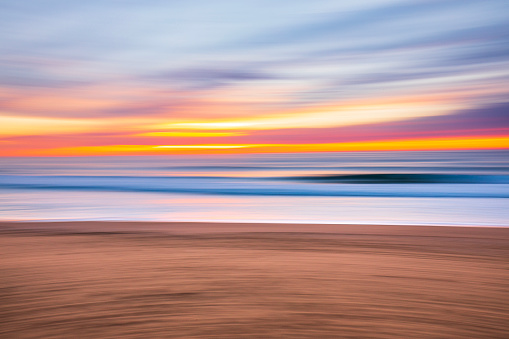 Motion blur pan seascape of the ocean shore at dusk with pastel colours.