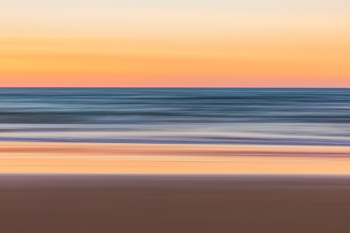 Motion blur pan seascape of the ocean shore at dusk with pastel colours.