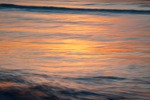 istock Close up of light reflecting on smooth ocean surface from sun setting 1496744352