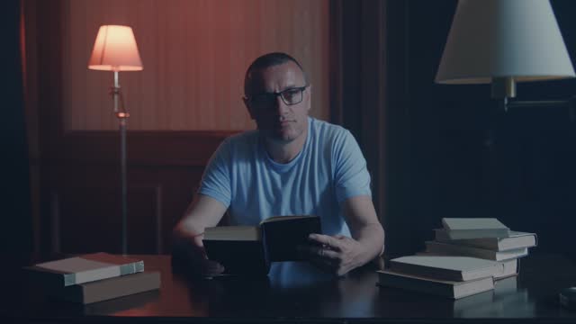 Man reading a book sitting on office desk, cine light shot
