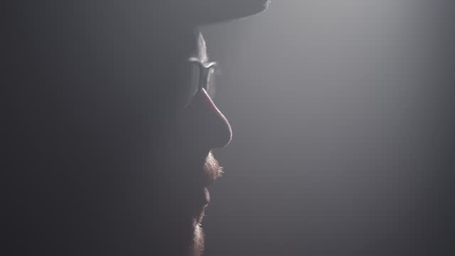 Night cinematic portrait of handsome entrepreneur retro English man with cap and beard fitting his flasses in slow motion