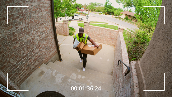 Packages being delivered to a home, as seen from a security camera.