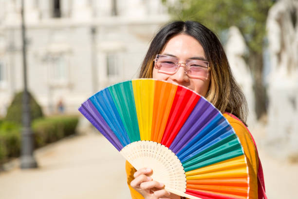 istock Young Asian hiding face with Pride fan 1496749348