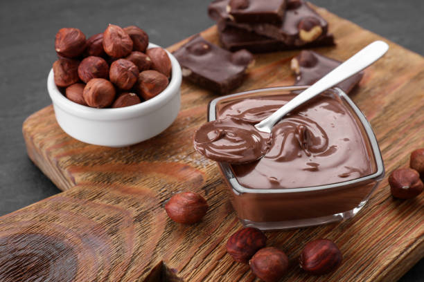 istock Bowl with tasty paste, chocolate pieces and nuts on wooden board, closeup 1496752265