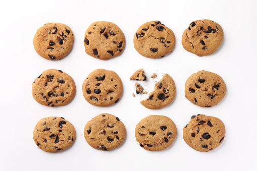 Many delicious chocolate chip cookies on white background, flat lay