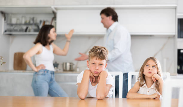 istock Frightened and frowning children sit at kitchen table during mom and dad quarrel. 1496752590