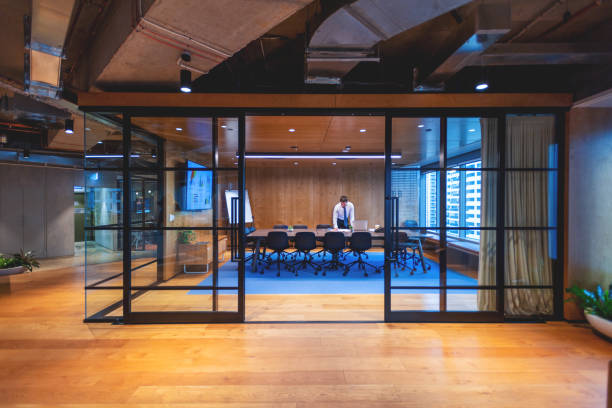 istock Business man standing and working in an office leaning on a conference table. He is standing in behind a board room table. 1496753018