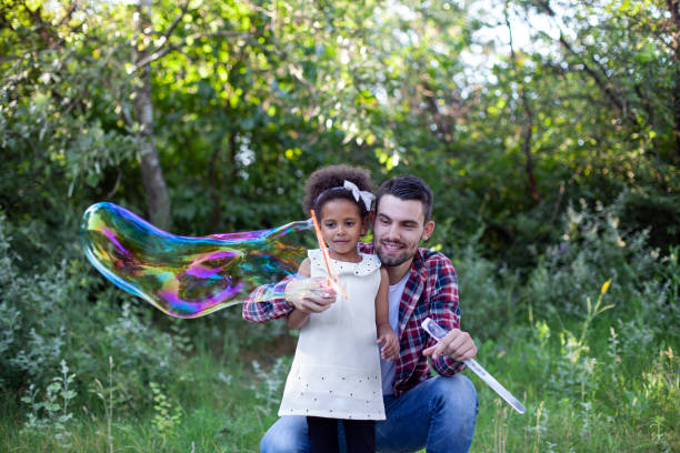 istock Happy father and daughter playing soap bubbles in park. 1496762916