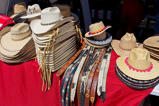 Group of hats and belt leather goods on display at festival. For sale in old town Mesilla New Mexico.