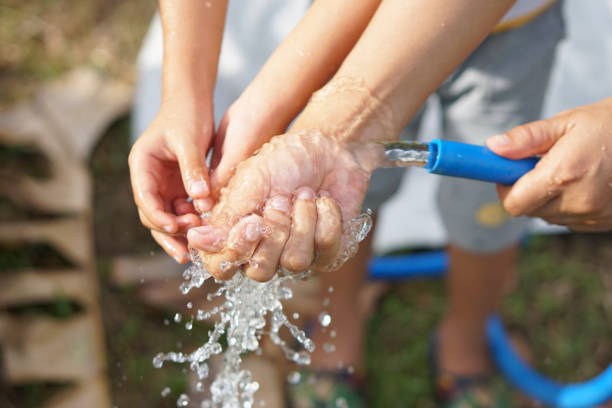 мать использует воду, чтобы вымыть руки своего ребенка. - human pregnancy baby shower image color image стоковые фото и изображения
