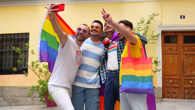 Homosexual male friends having fun at gay pride party taking a selfie, diversity of young people in the city, road to the demonstration with the rainbow flags, lgbt concept