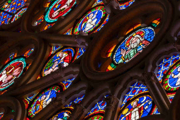 paneles de vidrieras de rosetón de la época medieval que muestran santos, ángeles en tracería gótica de piedra en una catedral - stained glass glass art church fotografías e imágenes de stock