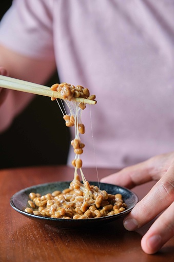 Unrecognizable man eating natto fermented soy beans with chopsticks. Japanese traditional food.