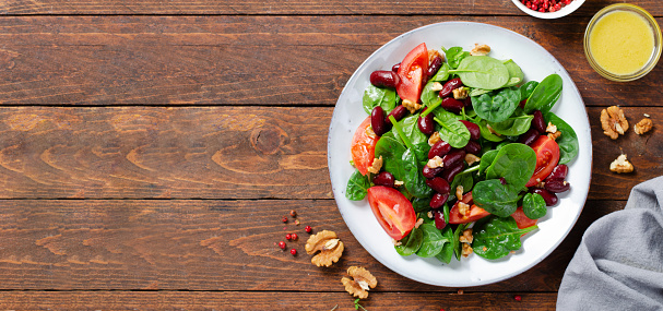 Red Bean Salad, Vegan Salad with Spinach, Cherry Tomatoes, Walnuts, Beans, and Mustard Dressing On Wooden Background