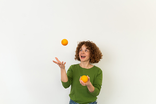 Studio portrait of a beautiful, young redhead woman holding a bunch of oranges