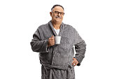 Smiling mature man wearing a grey robe and holding a cup
