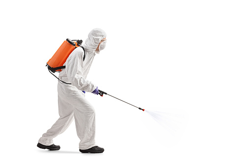 Full length profile shot of a man in a hazmat suit applying pesticide isolated on white background