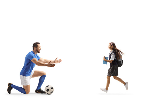 Schoolgirl running to hug a football player isolated on white background