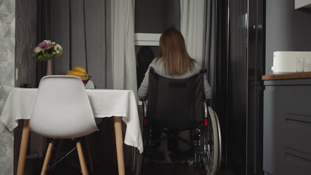 Housewife moves wheelchair closer to look out small window